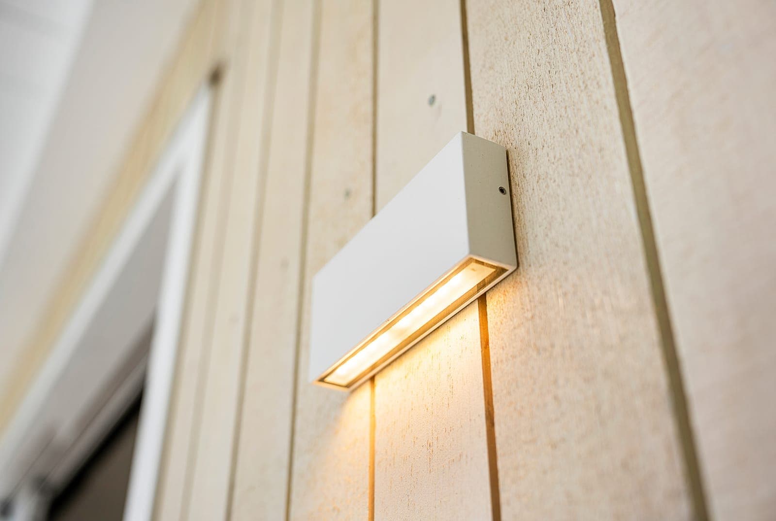 Modern new build interior detail — wall light on wooden slatted wall